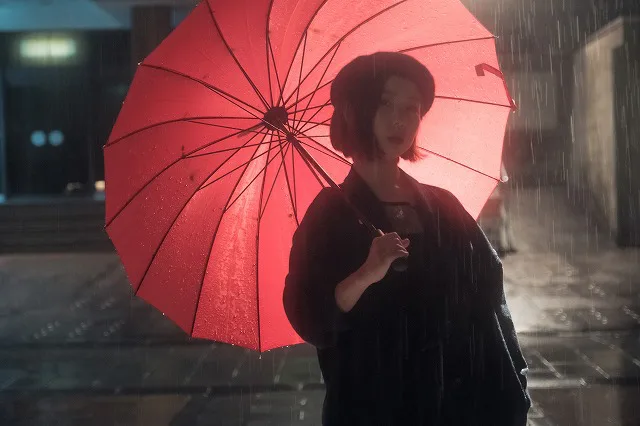 大雨の中赤い傘を持った女性を撮影